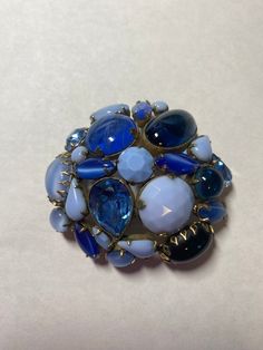 Vintage blue & gold signed Schreiner brooch. 6mm in diameter, combination of rhinestones and milky gems in blue tones in gold tone prong setting. AN ABSOLUTE STUNNER!  DON'T MISS THE PERFECT MATCHING SIGNED EARRINGS LISTED SEPARATELY! This belonged to my Grandma Ruth, born 1909. She was very tall and always sharply dressed--never without her signature bright red manicure and statement jewelry. I wear her engagement ring and wedding band every day, but I'm delighted to share some of her treasures! Blue Cabochon Brooch For Formal Occasions, Formal Blue Cabochon Brooch, Elegant Blue Jeweled Brooches, Unique Blue Brooches For Formal Occasions, Blue Cabochon Brooches For Wedding, Blue Round Brooch For Formal Occasions, Formal Blue Round Brooch, Formal Blue Round Brooches, Unique Blue Brooch For Party