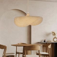 a dining room table and chairs in front of a wall with a circular light hanging over it