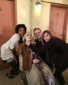 four people pose for a photo in front of a statue with a woman's face painted on it