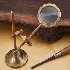 a magnifying glass sitting on top of a wooden table next to a pen