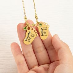 a person holding two gold necklaces with dog paw charms on it's sides