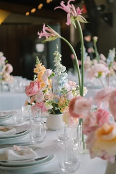 the table is set with flowers in vases and place settings for guests to sit at