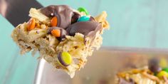 a spoon full of cereal bars with m & m candies on it and a fork in the background