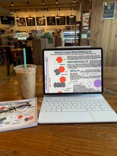 an open laptop computer sitting on top of a wooden table next to a cup of coffee