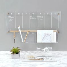 a white counter top with a plant on it and calendars attached to the wall