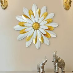 an elephant figurine stands in front of a wall with a flower on it