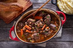 a pot filled with meat and carrots next to some bread