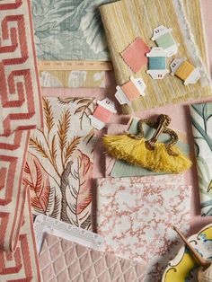 an assortment of fabric and other items on a pink table cloth with yellow tassels