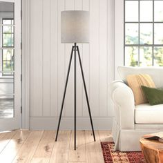 a living room with a white couch and wooden floor lamp in the middle of it