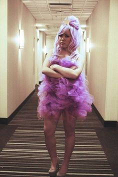 a woman in a purple dress is posing for the camera