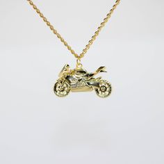 a gold necklace with a small motorcycle on it's back end and a chain attached to the front