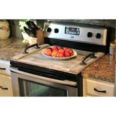 a bowl of fruit on a cutting board in front of an oven