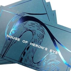 three blue business cards with the words house of herons eye on them, stacked together