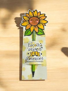 a pen that is sitting on top of a wooden table with a sunflower sticker attached to it