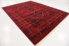 a large red rug with an intricate design on the top and bottom, laying on a white surface