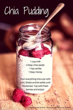 a jar filled with chia pudding next to raspberries on top of a wooden table