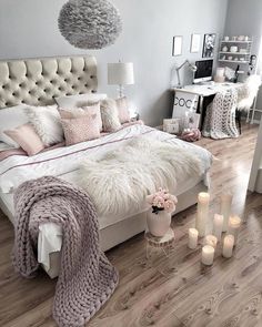 a bedroom decorated in white and pink with candles on the floor