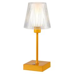 a yellow table lamp with a glass shade on it's base and a wooden block underneath