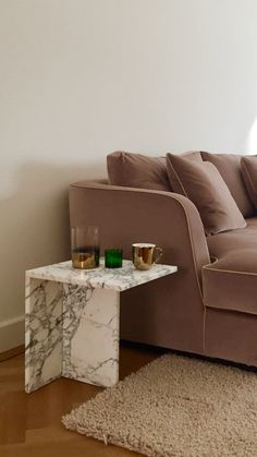 a marble table sitting on top of a wooden floor next to a couch