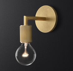 a light bulb mounted on the wall next to a black wall with a gold finish