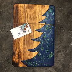 a wooden cutting board with a christmas tree on it and a tag hanging from the side