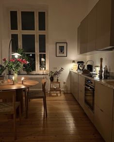 a kitchen with wooden floors and white walls is lit up by lights from the windows