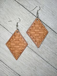 a pair of earrings made out of brown leather