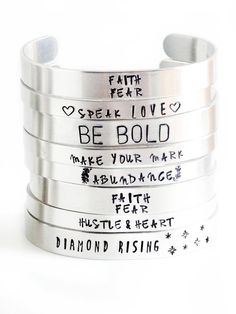 five silver bracelets with words written on them