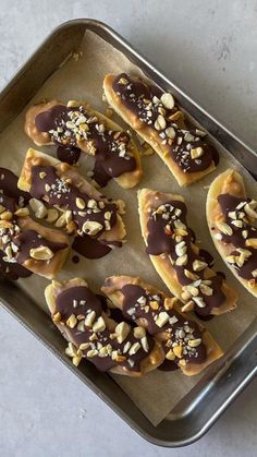 chocolate covered pretzels with nuts on top in a baking pan, ready to be eaten