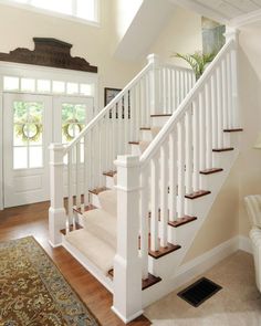 there is a white stair case in the living room with wood flooring and carpet