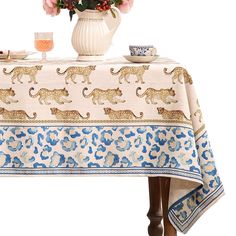 a table topped with a white vase filled with flowers next to a leopard print table cloth