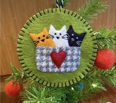 a christmas ornament with three cats in a pocket on it's side