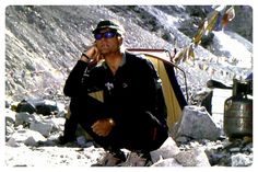 a man sitting on top of a rocky mountain next to a tent