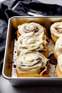 a pan filled with cinnamon rolls covered in icing