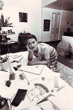 a woman sitting at a table with her hand on her face and looking up to the camera