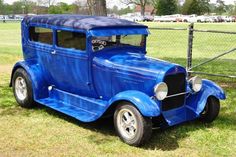 an old blue car is parked in the grass