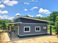 a small gray house sitting on top of a dirt field