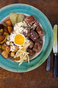 a blue plate topped with meat, potatoes and an egg