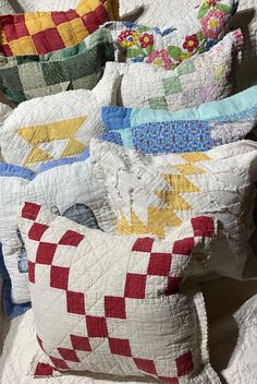 a pile of pillows sitting on top of a bed covered in quilts and blankets