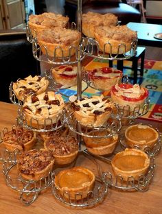 a table topped with lots of pies on top of metal racks and cups filled with toppings