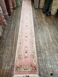 a long pink rug is on the floor in a room with many other rugs