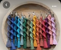 a bunch of different colored tassels on a wooden tray with metal hooks in the middle