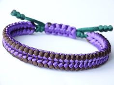 two purple and green braided bracelets sitting on top of each other