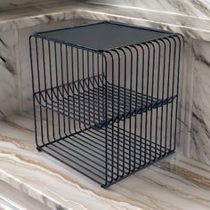 two black wire baskets sitting on top of a white marble counter next to each other