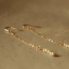 Long white pearl earrings on 14k gold filled chain, ear hook gold plated, wedding gift, gift for her, Wildbirds Jewerly.  Small natural freshwater pearls have been attached to a 4cm Gold Filled chain with a fine wire.  These earrings are a perfect gift for your bridesmaid. Each piece of WildbirdsJewerly is handmade to order in our small studio in Berlin. D E T A I L S 1 pair of earrings  14k Gold Filled 4cm chain Gold Filled wire Ear hook  5 pearls Total length about 7cm You can find more earrings here❤️ https://www.etsy.com/de/shop/WILDBIRDSJewelry?section_id=23561518 Gold Filled: This type of gold plating is the next best alternative to solid gold. It involves applying a 100x thicker layer of gold to a brass core. With good care and careful handling, your jewelry will last a lifetime. Ca Minimalist Gold Earrings With Pearl Chain, 14k Gold Filled Pearl Drop Earrings For Anniversary, Minimalist Gold Pearl Earrings With Pearl Chain, Minimalist Gold Pearl Earrings 14k Gold Filled, Gift Yellow Gold Long Drop Pearl Earrings, Minimalist Gold Pearl Earrings In 14k Gold Filled, Gold Linear Pearl Chain Earrings As Gift, Delicate Gold Linear Earrings For Anniversary, Minimalist 14k Gold Filled Pearl Earrings For Anniversary