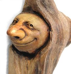 a wooden carving of a bear with its head sticking out from the tree trunk that has been carved to look like it is smiling