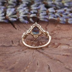 a close up of a ring on a piece of wood with lavender flowers in the background