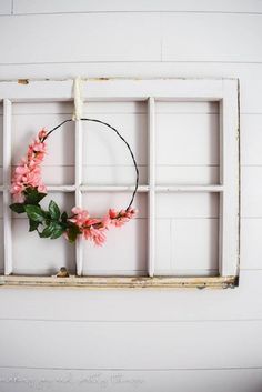 a window frame with flowers in it and a wreath hanging on the wall next to it