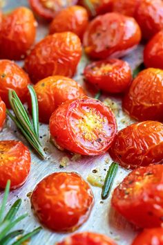 tomatoes and rosemary on a baking sheet ready to be cooked in the oven for roasting