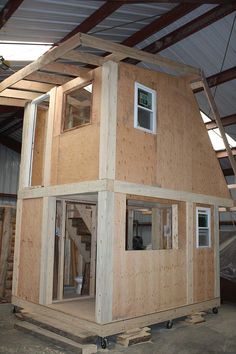 a house being built in the middle of a building with wooden walls and windows on each side